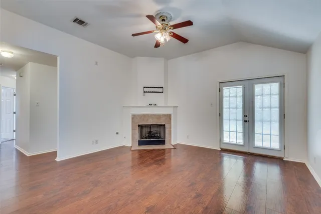 an empty room with windows fireplace and wooden floor