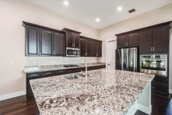 a large kitchen with granite countertop a sink stove and refrigerator