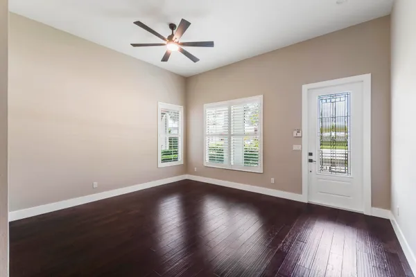 a view of an empty room with wooden floor and a window