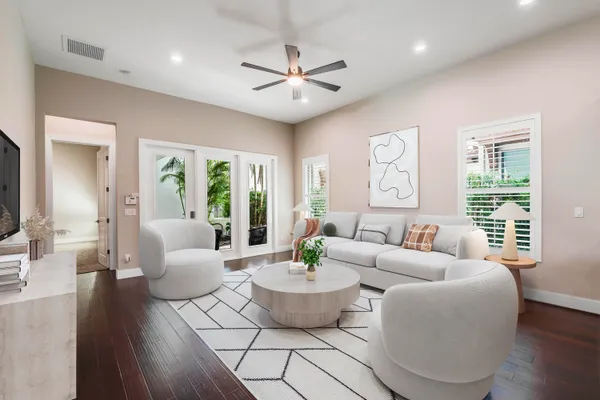 an empty room with wooden floor a ceiling fan and windows