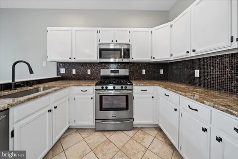 a kitchen with granite countertop white cabinets and appliances