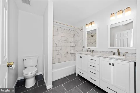 a bathroom with a double vanity sink mirror and toilet