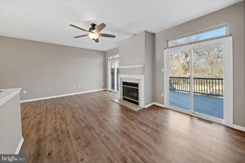 an empty room with wooden floor fan and windows