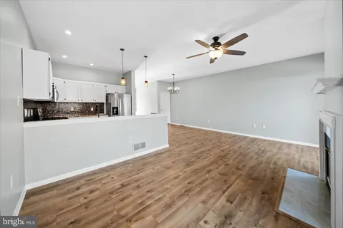 a view of a kitchen with kitchen island wooden floor center island and stainless steel appliances