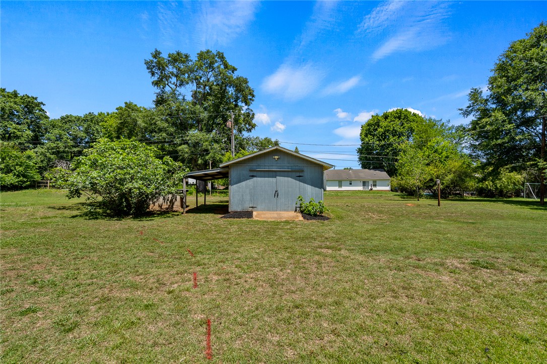 1509 869 Anderson, SC 29621 - Photo 44 of 45 A detached storage building with an open-sided lean-to sits amidst a spacious, green yard.