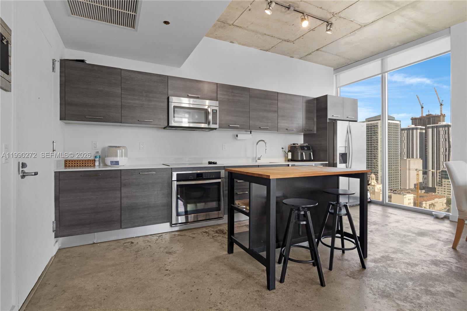 151 Southeast 1st Street, Unit 2802 Miami, FL 33131 - Photo 12 of 31 a kitchen with stainless steel appliances kitchen island granite countertop a table chairs sink and cabinets
