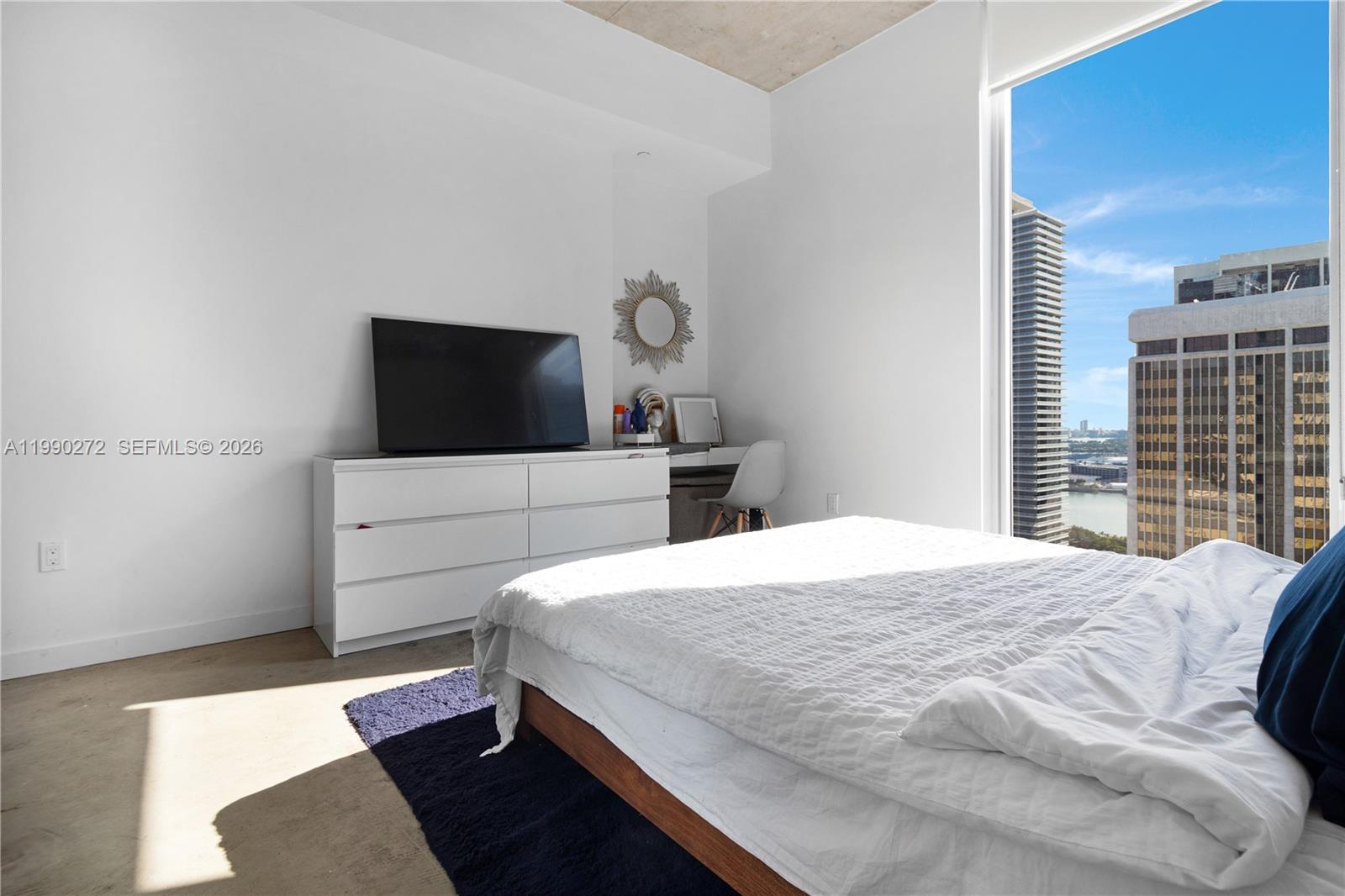 151 Southeast 1st Street, Unit 2802 Miami, FL 33131 - Photo 17 of 31 a bedroom with a bed and a flat tv screen on dresser