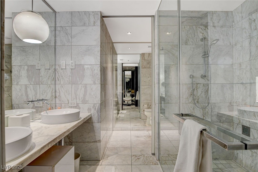 4381 West Flamingo Road, Unit 2202 Las Vegas, NV 89103 - Photo 25 of 40 Bathroom featuring tile walls, double vanity, a shower stall, and marble finish floors