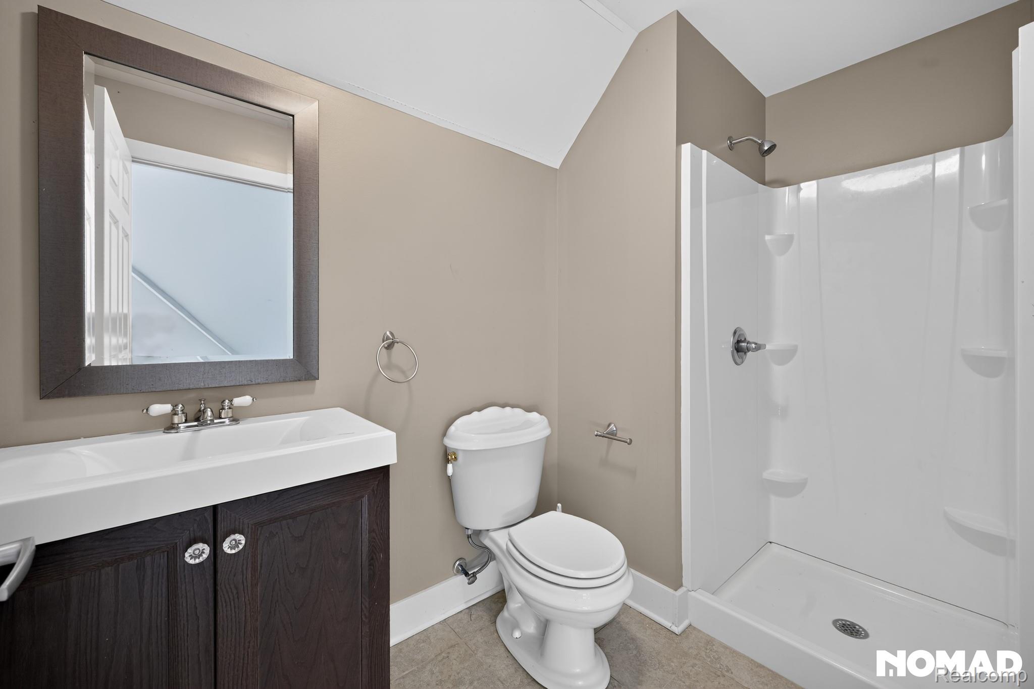 8315 Hilton Road Brighton, MI 48114 - Photo 22 of 26 Bathroom featuring a dark wood-finish vanity with an integrated white sink, a framed mirror, a two-piece toilet, and a white shower stall with a chrome showerhead