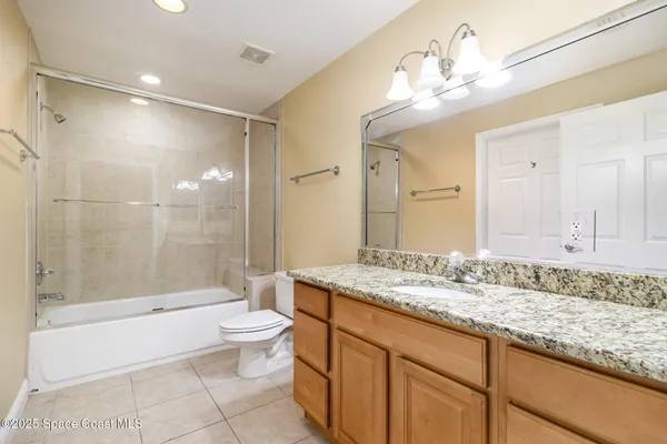 a bathroom with a granite countertop sink a toilet a mirror and bathtub