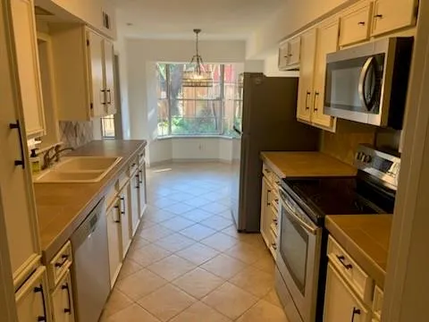 a kitchen with stainless steel appliances granite countertop a refrigerator a stove and a sink with wooden floor