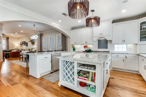 a kitchen with kitchen island granite countertop a stove a sink a oven and a refrigerator with cabinets