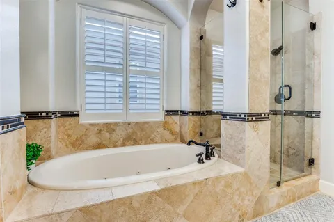 a spacious bathroom with a double vanity sink a mirror a bathtub and a shower