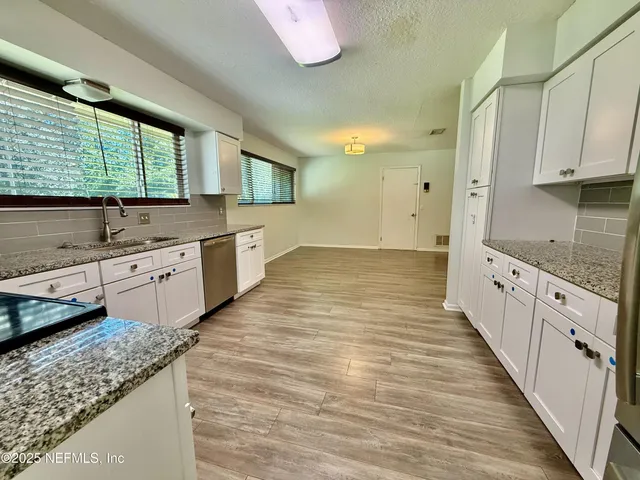 a large kitchen with stainless steel appliances granite countertop a sink and cabinets with wooden floor