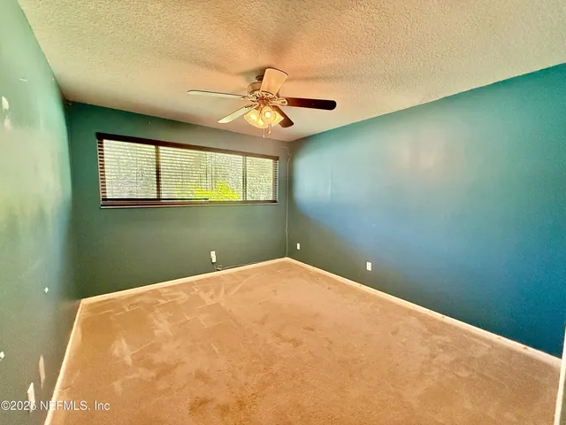 a view of a big room with windows and ceiling fan
