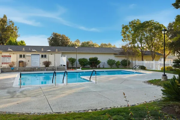 a view of a swimming pool with a lawn chairs under an umbrella