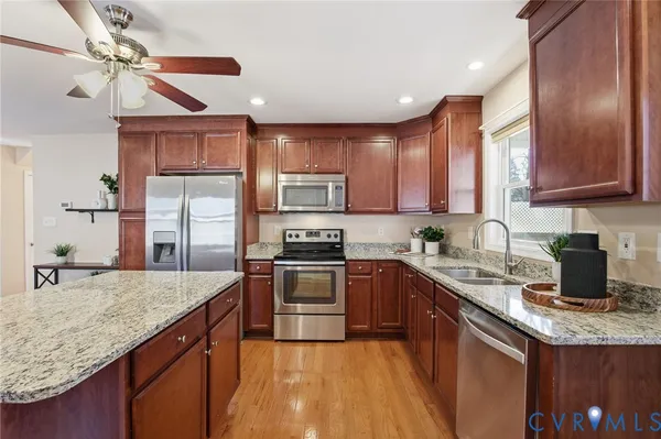 a kitchen with stainless steel appliances granite countertop a sink stove cabinets and refrigerator