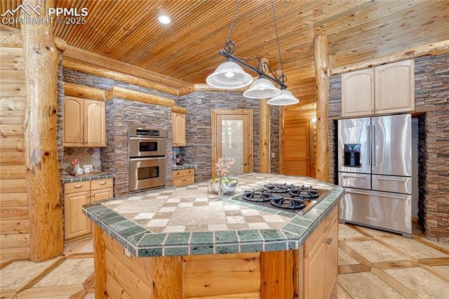 15975 Winding Trail Road Colorado Springs, CO 80908 - Photo 13 of 50 Island with 4 burner gas cooktop, a large refrigerator, walk-in pantry and double microwave / oven.