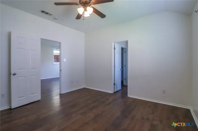 an empty room with wooden floor and a chandelier fan