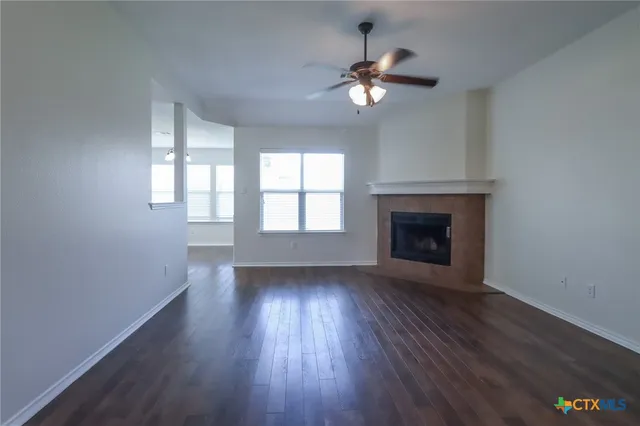 an empty room with wooden floor fireplace and windows