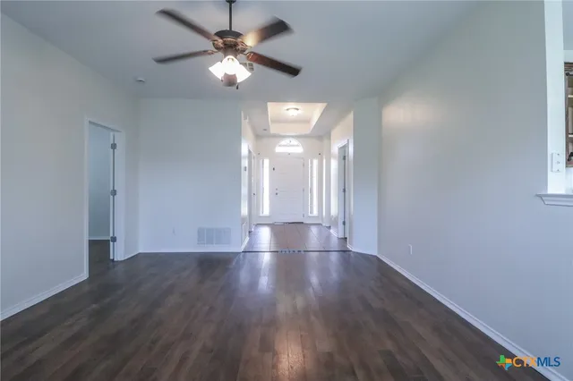 a view of an empty room with window and wooden floor