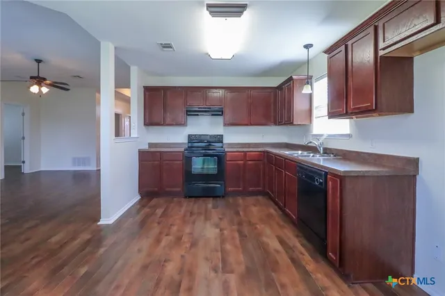 a kitchen with stainless steel appliances granite countertop wooden cabinets a sink a stove a refrigerator and island