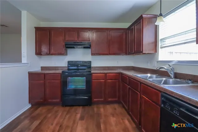 a kitchen with granite countertop wooden cabinets and a stove
