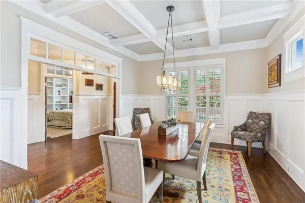 a kitchen with stainless steel appliances granite countertop a stove a refrigerator a kitchen island a dining table and chairs with wooden floor