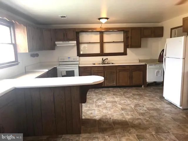 a kitchen with a refrigerator a sink dishwasher with a dining table and chairs