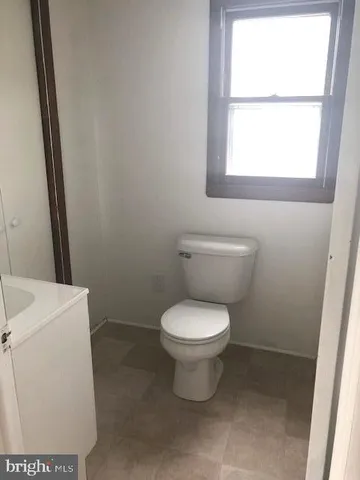 a white toilet sitting next to a window in a bathroom