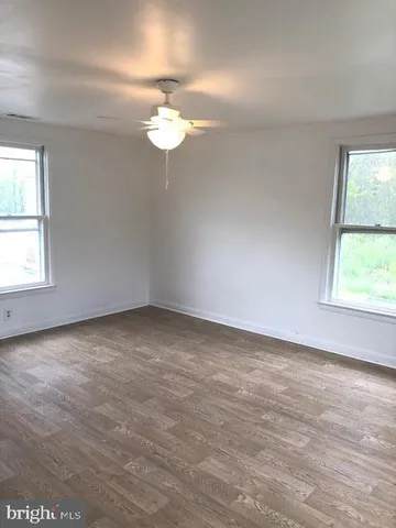 an empty room with a window and ceiling fan