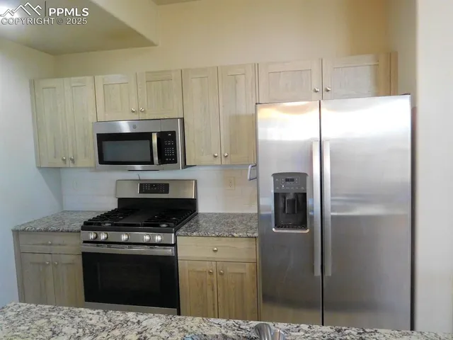 a kitchen with stainless steel appliances kitchen island granite countertop a refrigerator a stove and a sink