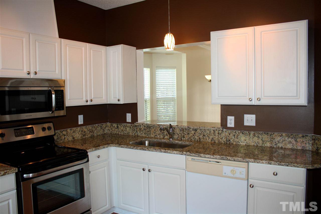 4435 Still Pines Drive Raleigh, NC 27613 - Photo 5 of 19 a kitchen with granite countertop white cabinets and black appliances