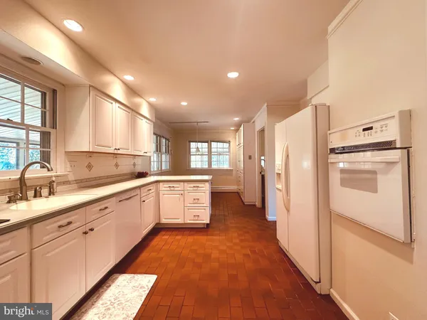 a kitchen with a sink dishwasher a stove and white cabinets with wooden floor