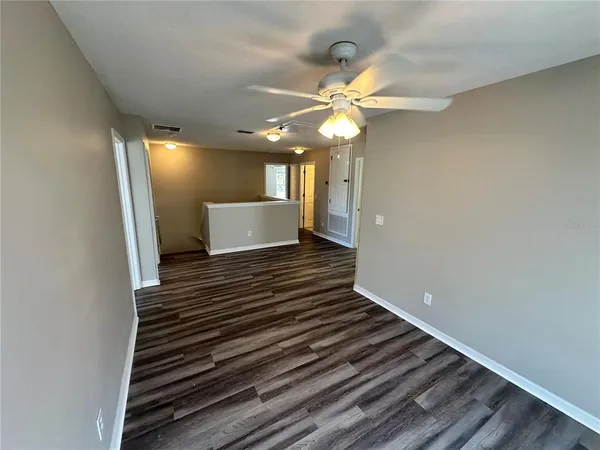 a view of an empty room with window and a ceiling fan