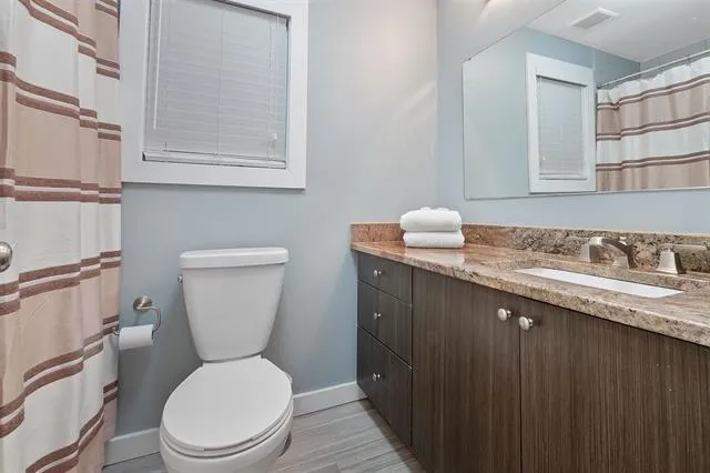 a bathroom with a granite countertop toilet sink and mirror