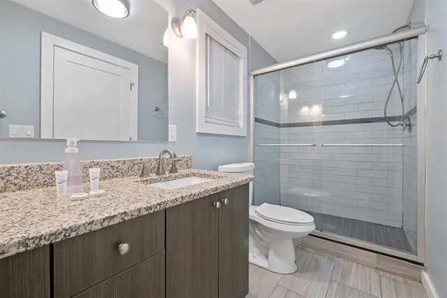 a bathroom with a granite countertop sink toilet and shower