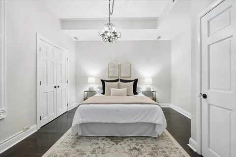 a large bed in a white room with a chandelier