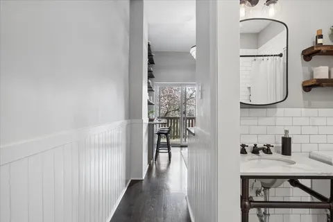 a view of a hallway with wooden floor and a bathroom