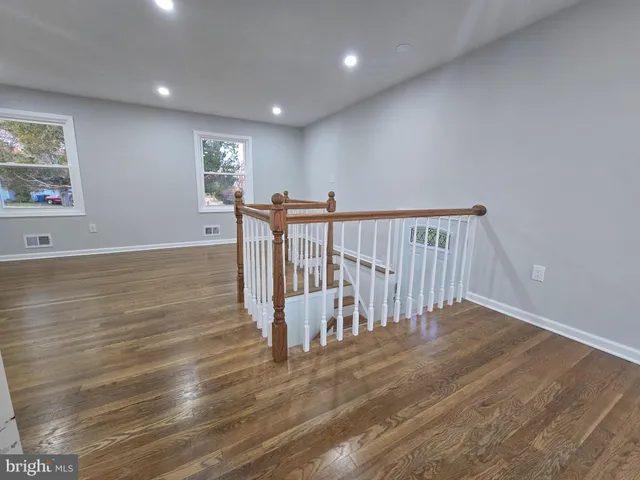 a large white kitchen with wooden floors and stainless steel appliances