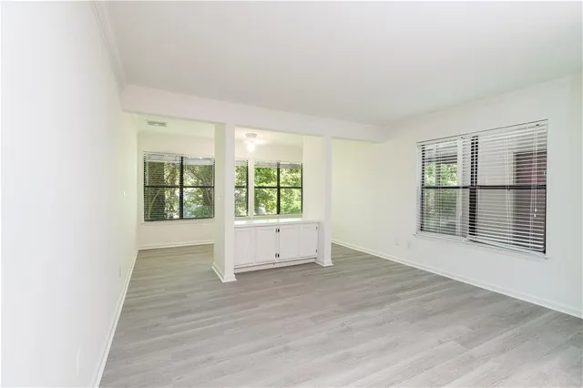 a view of an empty room with wooden floor and a window