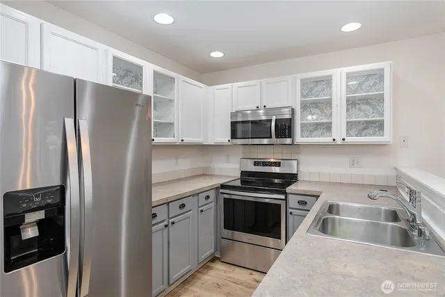 a kitchen with stainless steel appliances granite countertop a refrigerator a sink a stove a microwave and island