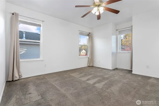 an empty room with chandelier fan and windows