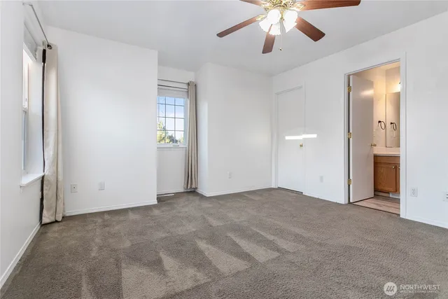 an empty room with chandelier fan and windows