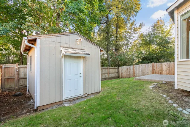 a view of backyard with small cabin and wooden fence