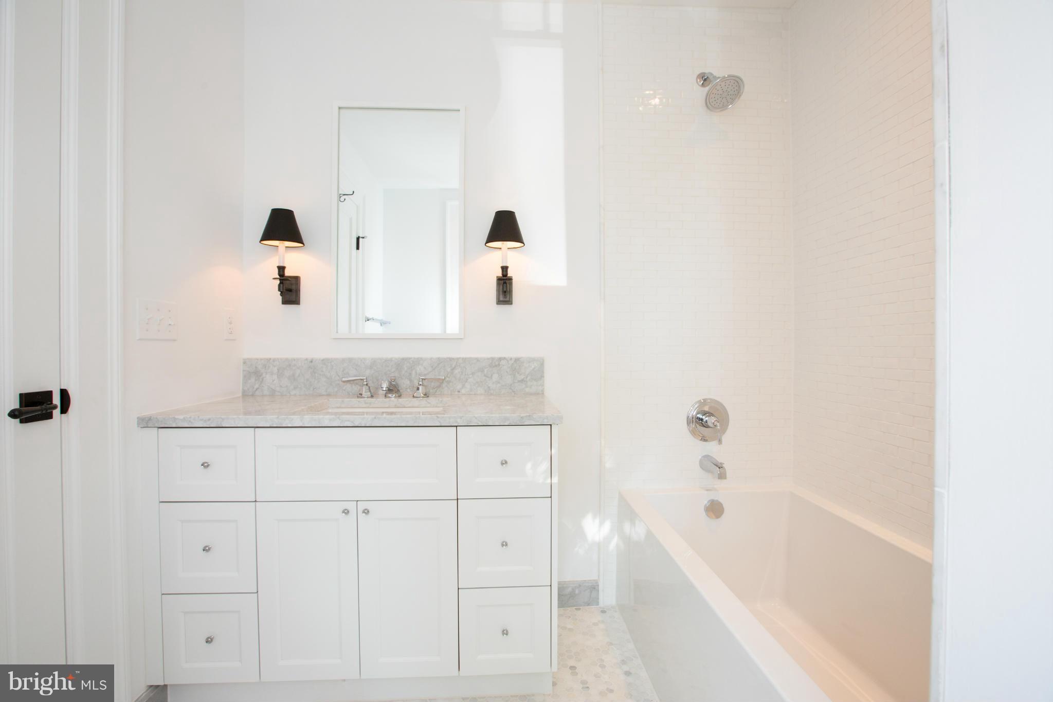 541 7th Street Southeast Washington, DC 20003 - Photo 15 of 30 a bathroom with a granite countertop sink a mirror a bathtub and shower
