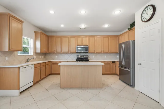 a kitchen with stainless steel appliances granite countertop a refrigerator and a stove top oven
