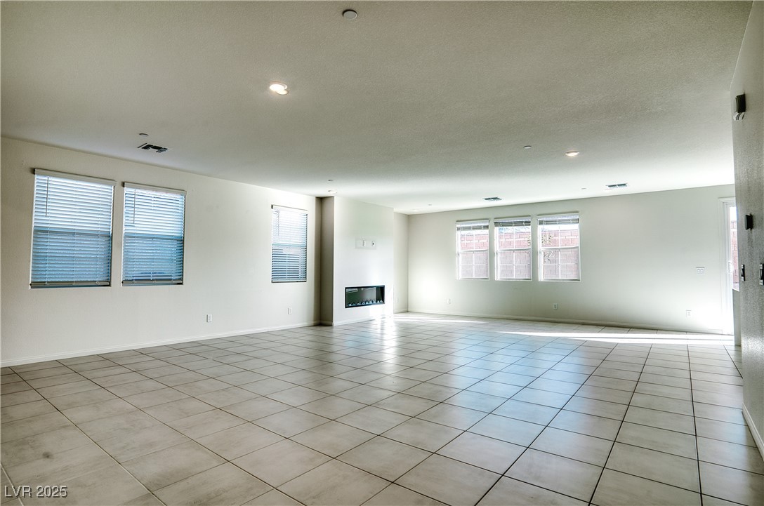 3777 Alla Rocca Avenue Henderson, NV 89044 - Photo 11 of 55 Unfurnished living room featuring tile patterned flooring, a glass covered fireplace, and recessed lighting