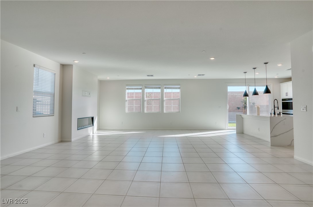 3777 Alla Rocca Avenue Henderson, NV 89044 - Photo 12 of 55 Unfurnished living room featuring light tile patterned floors, recessed lighting, and a glass covered fireplace
