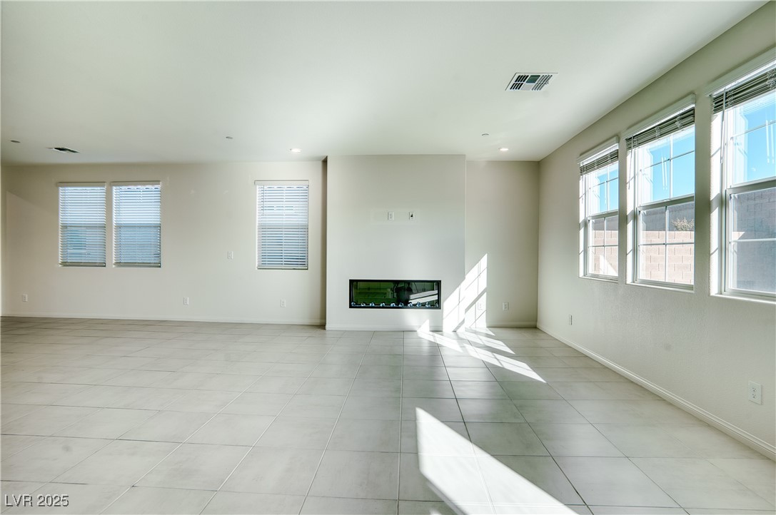 3777 Alla Rocca Avenue Henderson, NV 89044 - Photo 10 of 55 Unfurnished living room with plenty of natural light, a glass covered fireplace, light tile patterned floors, and recessed lighting